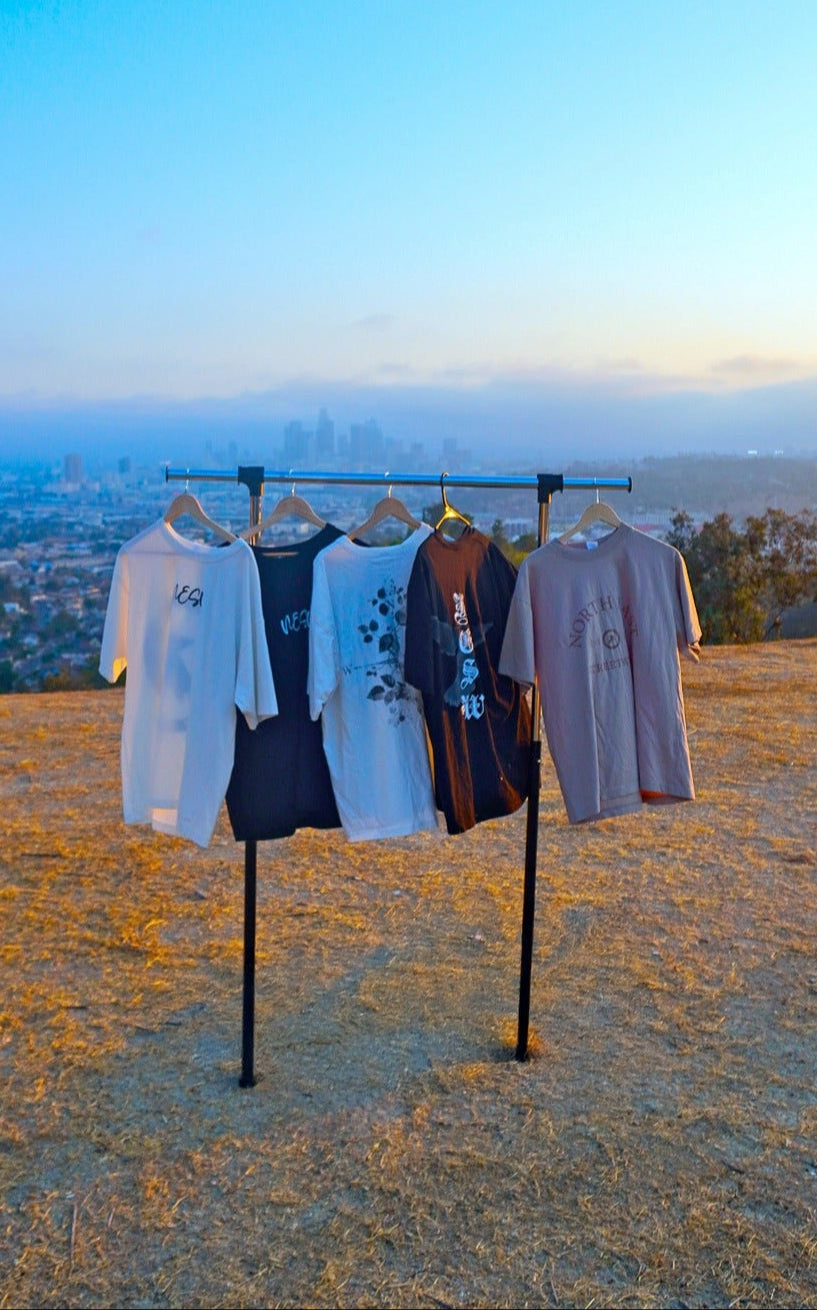 Clothing rack with clothes against a scenic backdrop of a city skyline at sunset.